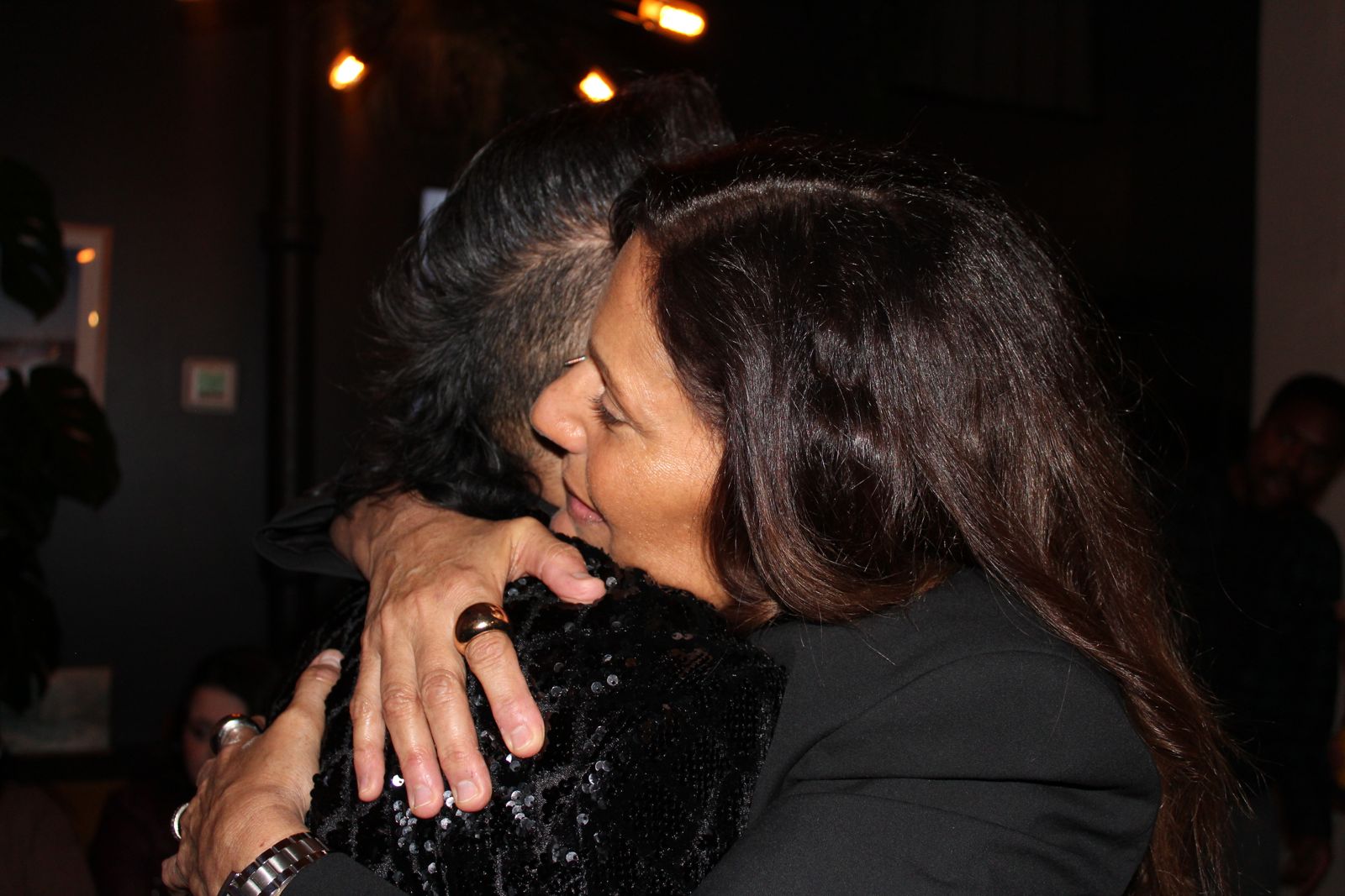 Two guests embracing at an evening event